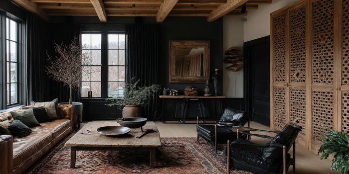 Rustic living room with leather sofa, reclaimed wood coffee table, black armchairs, patterned rug, and back wall styled with reclaimed console tables and decor.